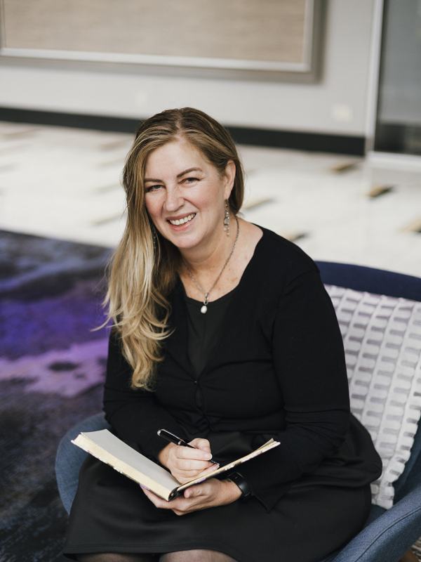 Sharon Hayward sitting on a chair with a opened book.